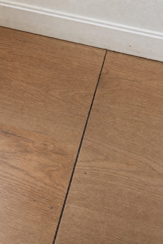 Close view of a thin dark gap opened between two peel and stick floor tiles