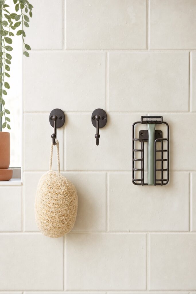 Bathroom wall with espresso hooks and a slotted open holder letting a razor and loofah air-dry