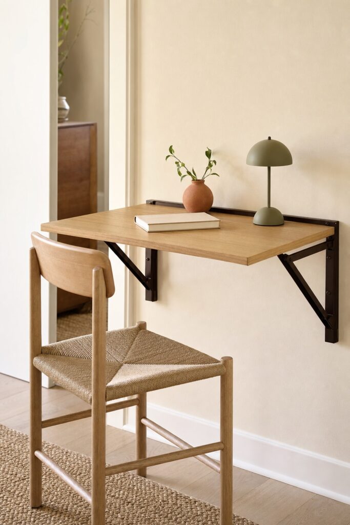 Wall-mounted drop-down desk surface lowered on its brackets in a very small room