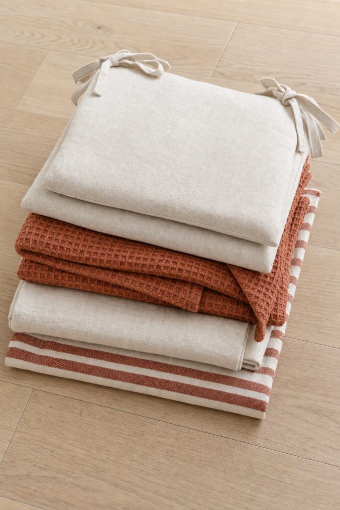 Kitchen textiles laid out together runner towels cafe curtain and seat pads in one palette